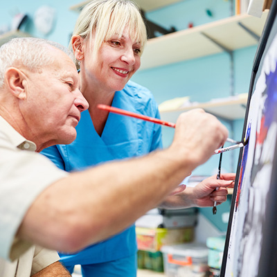Nurse helping patient paint