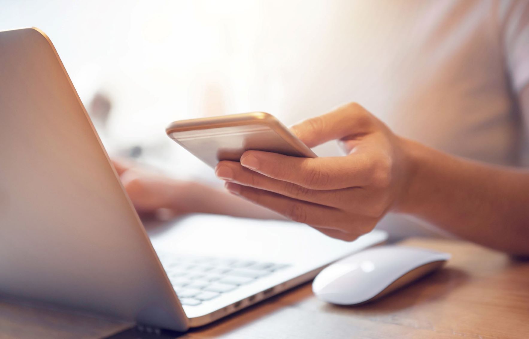 Person loooking at phone and laptop