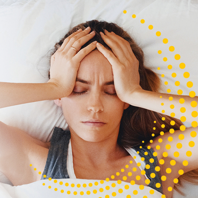 Person laying in bed and holding their head